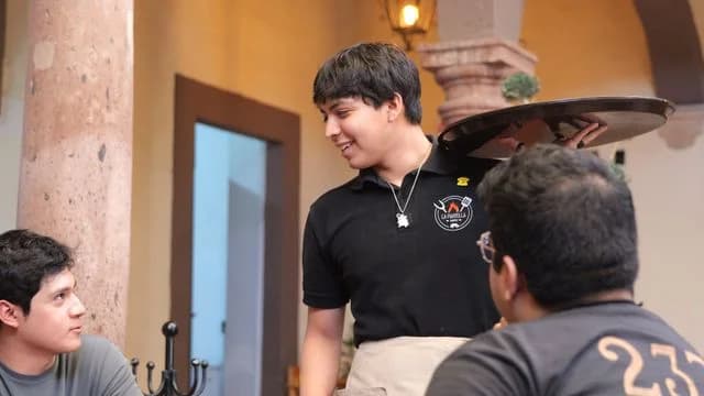 Mesero invitando a un cliente a escanear el codigo QR del menu